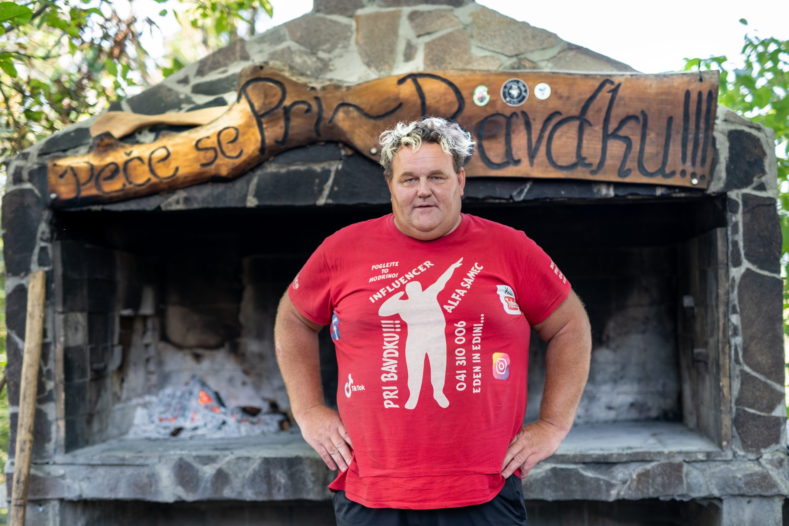 Aleš Bavdek pred kaminom z napisom Peče se pri Bavdku